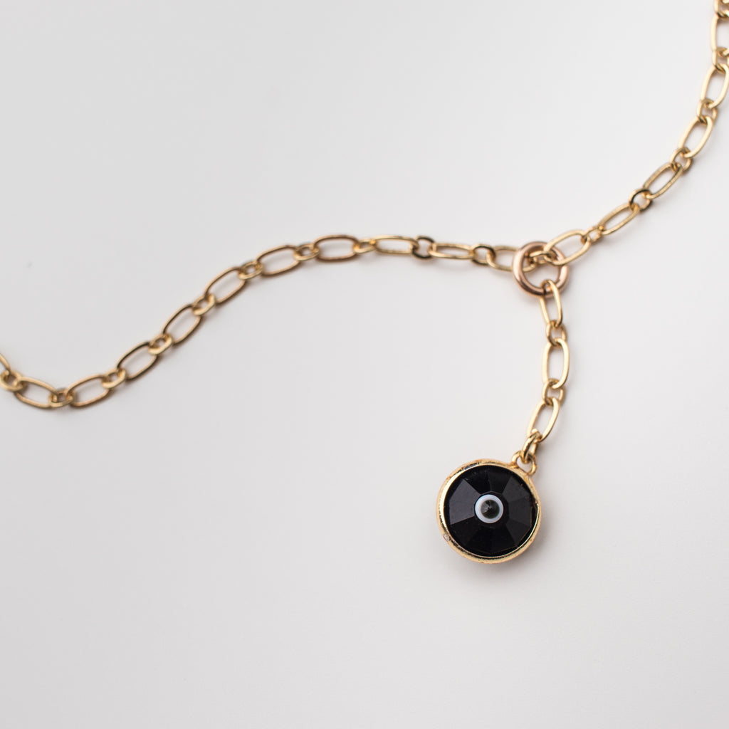 Gold necklace with black coloured crystal eye charm.