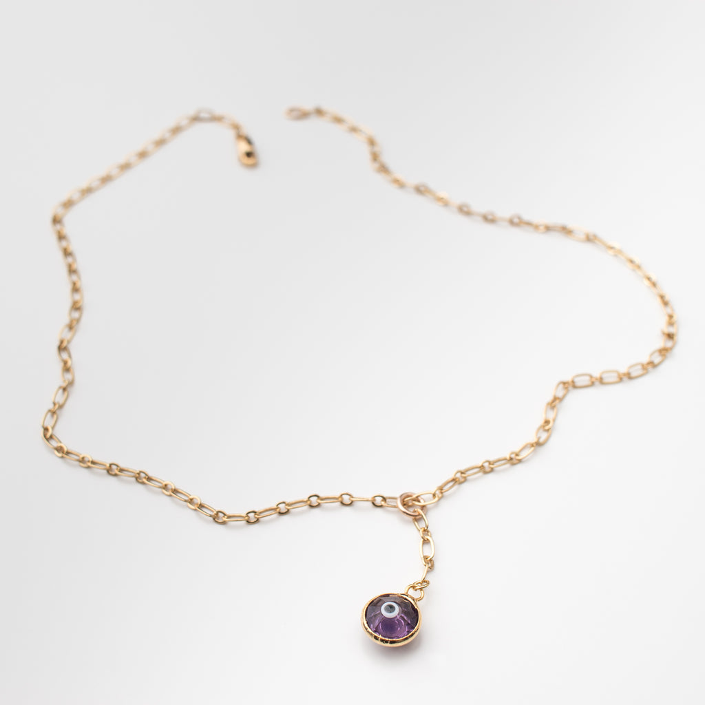Gold necklace with purple coloured crystal eye charm.