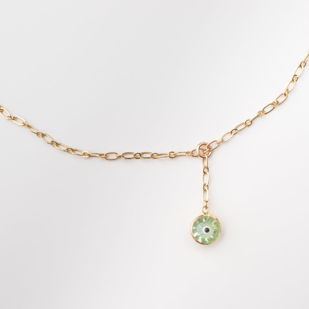 Gold necklace with light green coloured crystal eye charm.