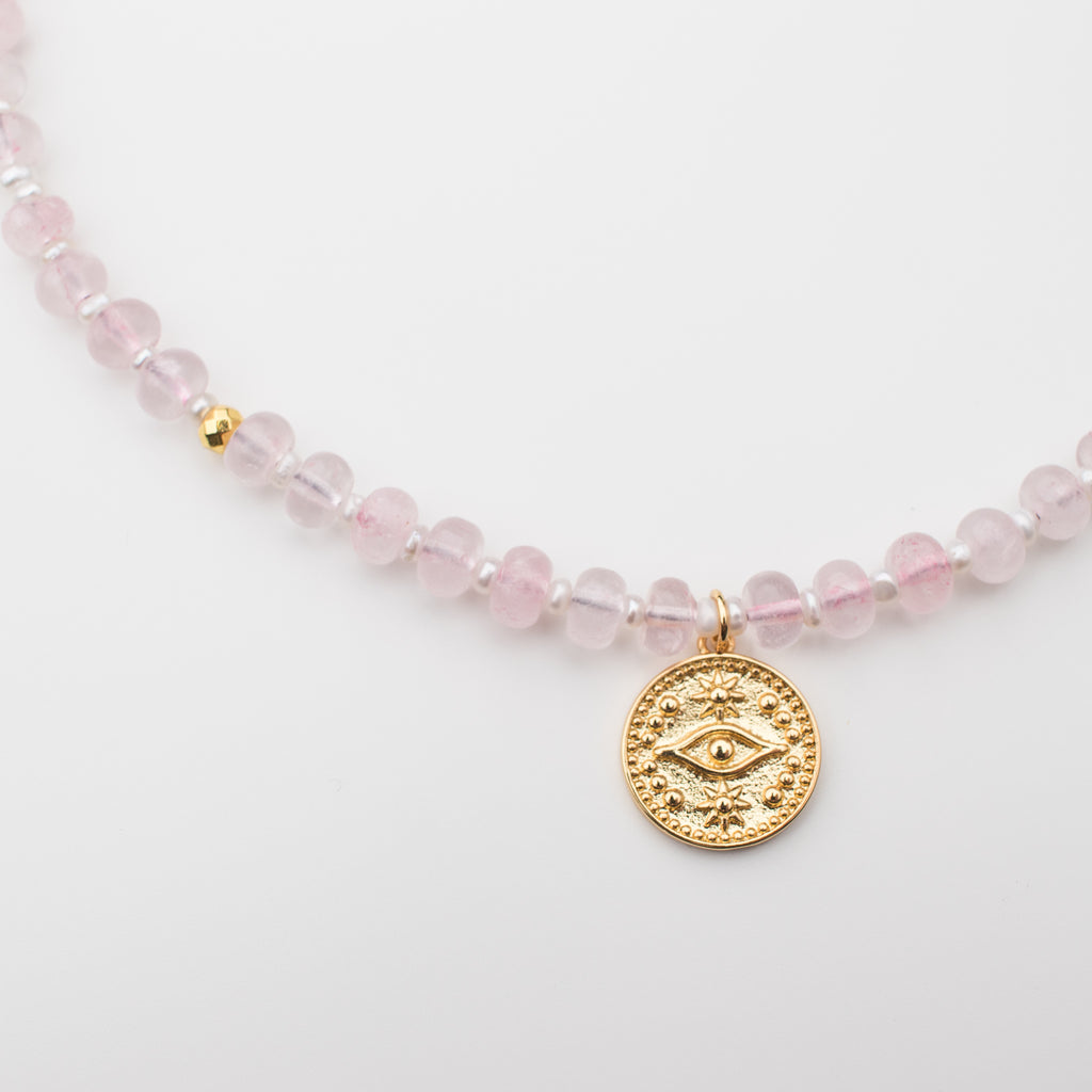 Pink gemstone necklace with rose quartz disk stones, mini freshwater pearls and gold embellishments. Pendant is a gold filled evil eye that is tarnish resistant. 
