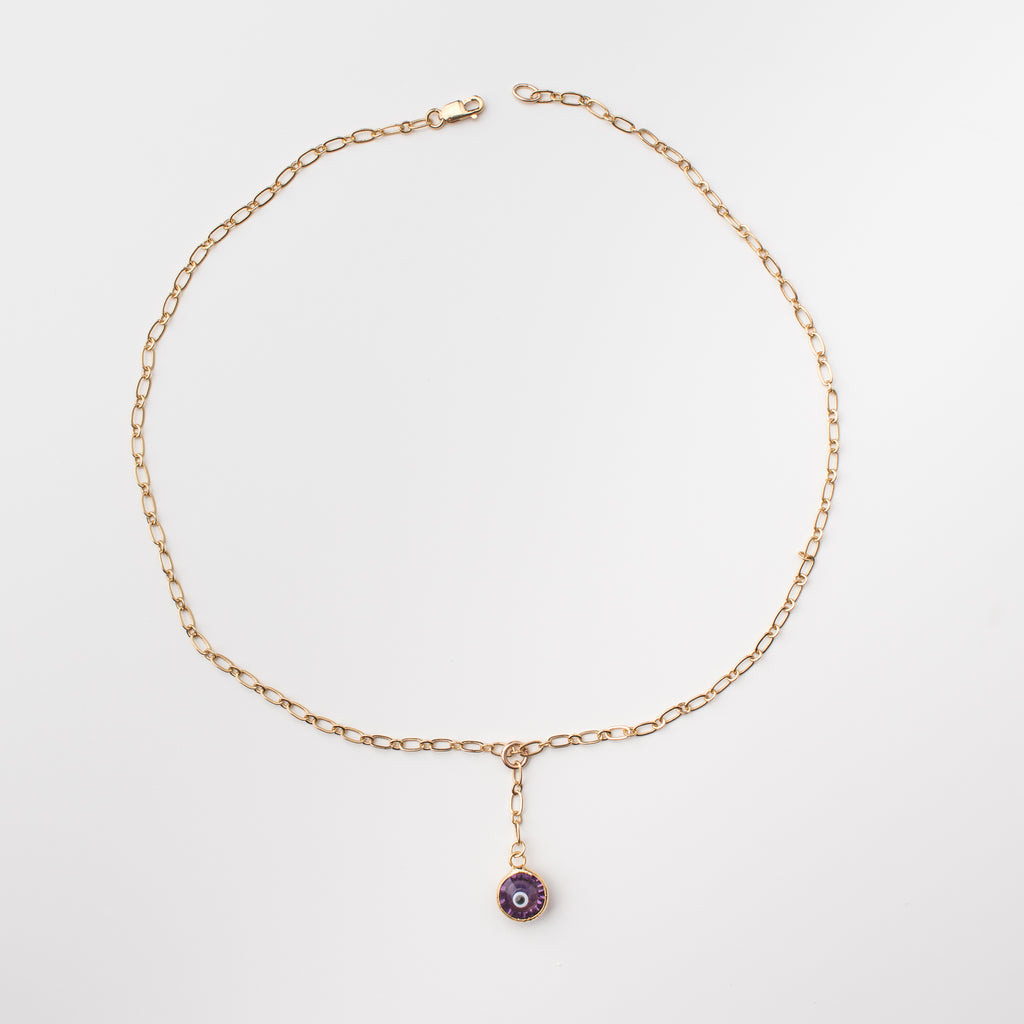 Gold necklace with purple coloured crystal eye charm.