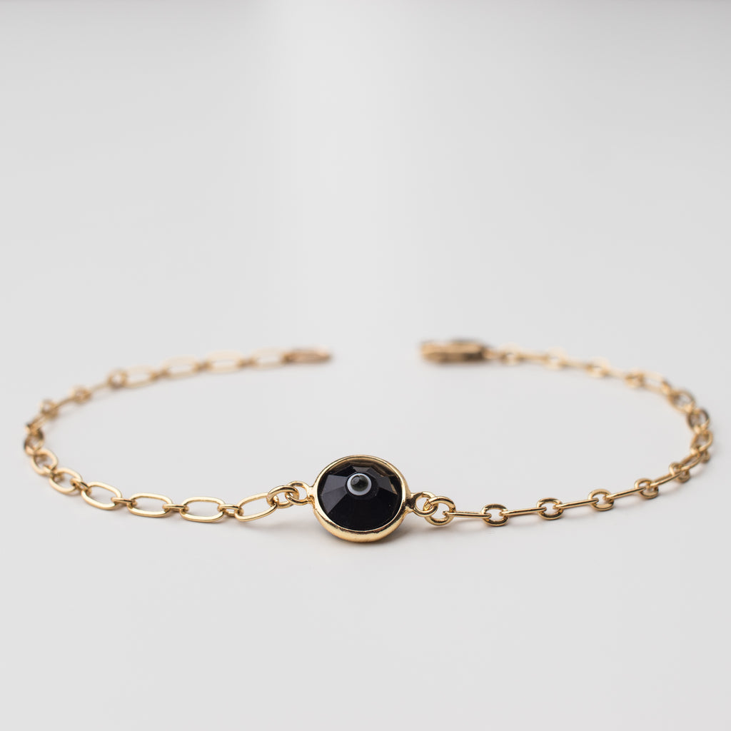 Gold bracelet with black eye crystal charm.